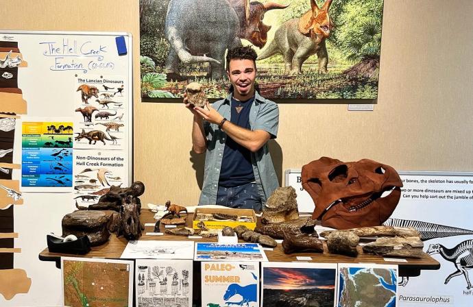 A man holds up a fossil running a museum activity for a family