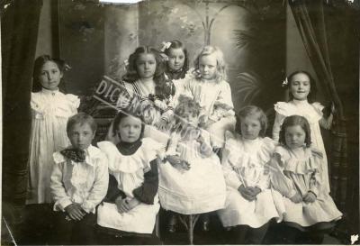 Sepia tone group photo of nine children (eight girls and one boy).